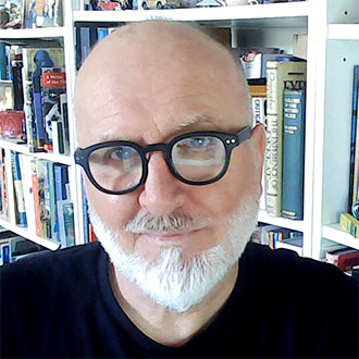 man with glasses in front of book cases 