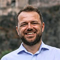 head and shoulders colour photo of a man with a beard smiling