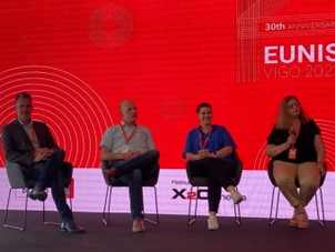 four people sitting on chairs on a stage